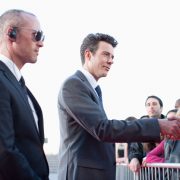 Politician shaking hands with people behind barrier